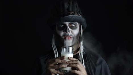 Creepy-man-with-skeleton-makeup-in-top-hat.-Guy-looking-at-camera,-drinks-milk-from-a-glass