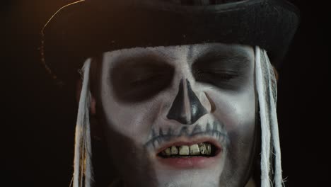 Man-with-skeleton-creepy-makeup-trying-to-scare,-opening-his-mouth-and-showing-dirty-black-teeth