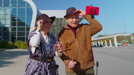 Retired-family-couple-making-selfie-or-technology-video-call-on-mobile-phone-to-family-near-airport