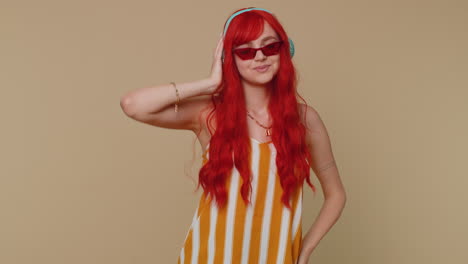 Cheerful-redhead-woman-listening-music-via-headphones-and-dancing-disco-fooling-around-having-fun