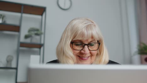 Una-Mujer-De-Negocios-Senior-Usa-Gafas-Trabajando-En-La-Oficina-Del-Hogar,-Seminario-Web-En-Línea-Usando-Una-Computadora-Portátil