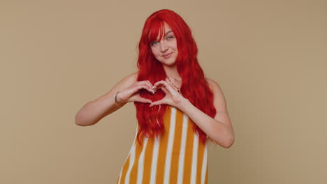 Smiling-ginger-girl-makes-heart-gesture-demonstrates-love-sign-expresses-good-feelings-and-sympathy