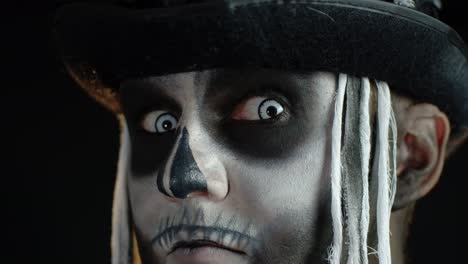 Close-up-shot-of-creepy-man-in-skeleton-Halloween-makeup-opening-eyes-and-looking-spooky-at-camera
