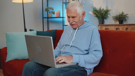 Ein-Glücklicher-älterer-Mann,-Der-Am-Laptop-Arbeitet,-Feiert-Seinen-Erfolg-Und-Gewinnt-Geld-Im-Lotto.-Er-Erhält-Online-Gute-Nachrichten