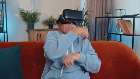 Senior-man-using-virtual-reality-futuristic-technology-headset-play-simulation-3D-video-game-at-home