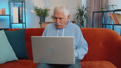 Älterer-Großvater-Sitzt-Auf-Dem-Sofa-Und-Schließt-Den-Laptop-PC,-Nachdem-Er-Die-Arbeit-Im-Wohnzimmer-Zu-Hause-Beendet-Hat