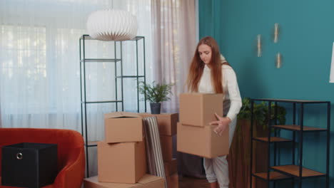 Young-woman-unpacking-cardboard-boxes-with-interior-furniture-after-buying-new-apartment-home-house