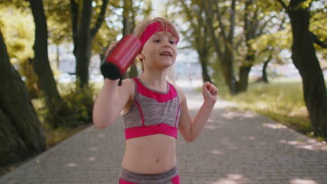 Sport-runner-jogger-child-girl-listen-bluetooth-music-speaker-dancing-to-camera-having-fun-in-park