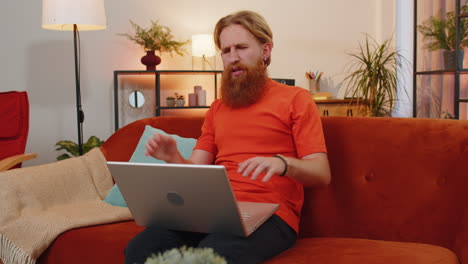 Bearded-redhead-man-use-laptop-surprised-by-bad-news,-fortune-loss,-fail,-lottery-results-at-home