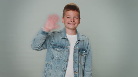 Toddler-boy-smiling-friendly-at-camera-and-waving-hands-gesturing-hello-or-goodbye,-welcoming