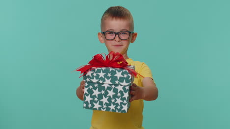 Smiling-toddler-children-boy-presenting-birthday-gift-box-stretches-out-hands,-offer-wrapped-present