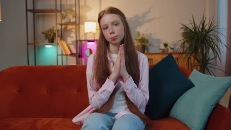 Young-redhead-child-girl-praying-sincerely-with-folded-arms-asking-God-for-help,-begging-apology