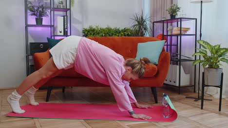 Young-woman-doing-yoga-stretching-excersices-on-mat,-workout,-burning-fat-calories,-training-at-home