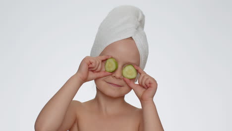 Lächelndes-Kind-Hält-Gurkenscheiben-In-Der-Hand,-Bedeckt-Die-Augen,-Naturkosmetik,-Gesichtspflege
