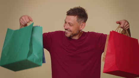 Glücklich-Lächelnder-Junger-Mann-Zeigt-Einkaufstüten,-Werberabatte,-Erstaunt-über-Niedrige-Preise