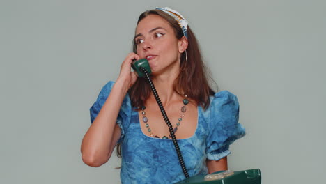 Crazy-girl-in-blue-dress-talking-on-wired-vintage-telephone-of-80s,-fooling-making-silly-faces