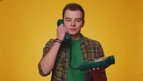 Cheerful-tourist-man-secretary-talking-on-wired-vintage-telephone-of-80s,-says-hey-you-call-me-back