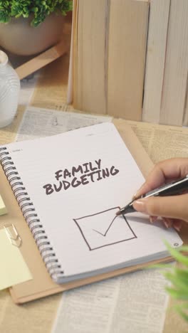 VERTICAL-VIDEO-OF-TICKING-OFF-FAMILY-BUDGETING-WORK-FROM-CHECKLIST