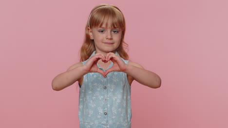 Smiling-preteen-child-girl-kid-makes-heart-gesture-demonstrates-love-sign-expresses-good-feelings