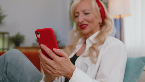 Senior-woman-using-smartphone-show-thumbs-up-like,-positive-feedback,-recommends-wifi-connection-5G
