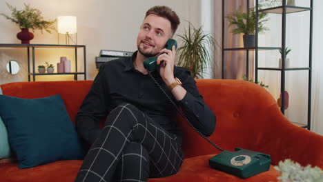 Man-making-retro-telephone-from-90s-conversation-with-friends-sitting-call-on-couch-at-home-in-room