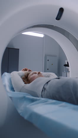 Vertikale-Aufnahme-Einer-Frau,-Die-Auf-Einer-CT-,-PET--Oder-MRT-Untersuchungsliege-Liegt-Und-Sich-Im-Gerät-Bewegt.-Scannen-Des-Körpers-Und-Gehirns-Des-Patienten-Mit-Hochmoderner-Hightech-Ausrüstung.-Medizinisches-Labor-Mit-Fortschrittlichen-Technologien.