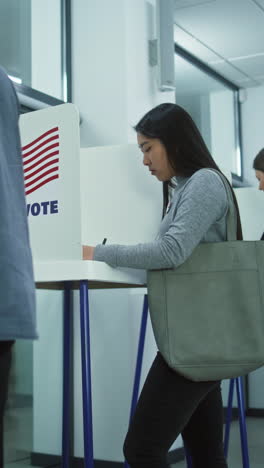 Multicultural-voters,-US-people-vote-in-voting-booths-at-polling-station.-Indian-man-puts-ballot-paper-in-box.-National-Election-Day-in-the-United-States-of-America.-Civic-duty-and-patriotism-concept.