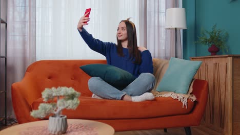 Frau-Auf-Dem-Sofa-Zu-Hause-Mit-Smartphone-Macht-Selfie-Mit-Der-Handykamera,-Virtueller-Videoanruf-Online