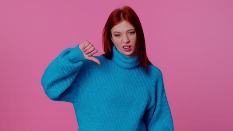 Upset-girl-in-blue-sweater-showing-thumbs-down-sign-gesture,-disapproval,-dissatisfied,-dislike