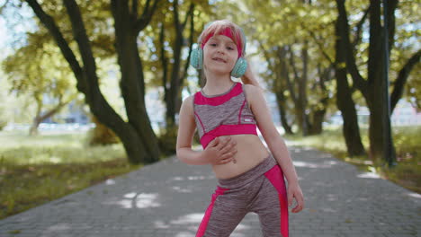 Sport-runner-child-girl-training-exercise-listening-music-on-headphones-dancing-to-camera-having-fun