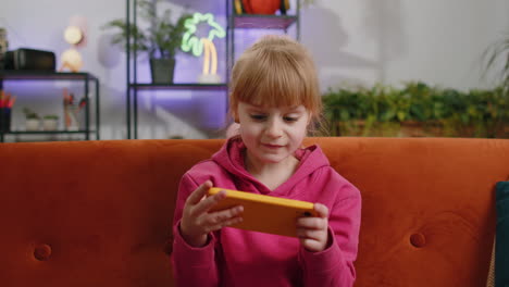 Worried-funny-child-kid-girl-playing-online-racing-simulator-or-shooter-video-games-on-smartphone