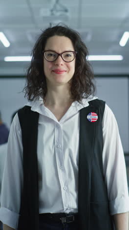 Woman-in-camouflage-uniform-stands-in-polling-station-and-looks-at-camera.-Portrait-of-female-soldier,-United-States-of-America-elections-voter.-Background-with-voting-booths.-Concept-of-civic-duty.