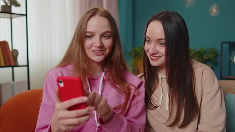 Two-female-woman-friends-family-watching-funny-movies-on-smartphone,-online-comedy-film-at-home