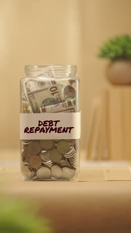 VERTICAL-VIDEO-OF-PERSON-SAVING-MONEY-FOR-DEBT-REPAYMENT