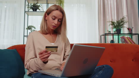 Young-woman-using-credit-bank-card-and-laptop,-transferring-money,-purchases-online-shopping