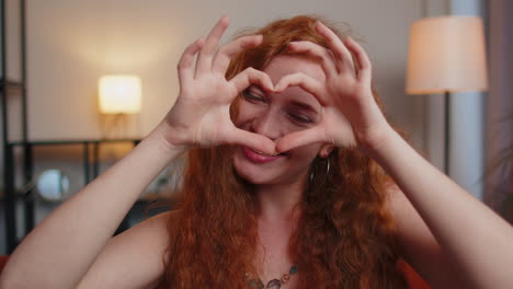 Redhead-young-woman-makes-symbol-of-love,-showing-heart-sign-to-camera,-express-romantic-feelings
