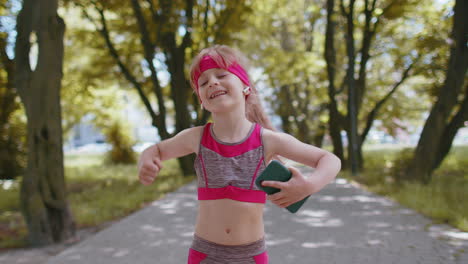 Athletic-fitness-sport-runner-child-girl-walking,-using-smartphone-listening-music-with-earphones