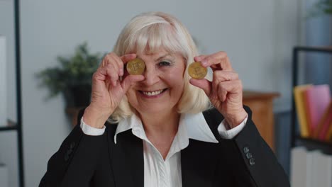Elderly-businesswoman-showing-golden-bitcoins-BTC,-money-mining,-investment,-wealth,-earning,-income