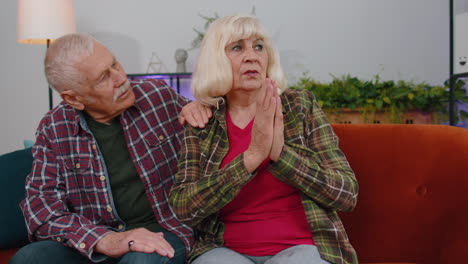 Senior-elderly-family-couple-grandparents-man-woman-pray-with-hope,-making-wish,-begging-apology