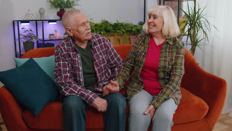 Cheerful-senior-family-couple-grandparents-man-woman-having-pleasant-loving-conversation-at-home