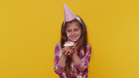 Happy-child-girl-kid-celebrating-birthday-party,-makes-wish-blowing-burning-candle-on-small-cupcake