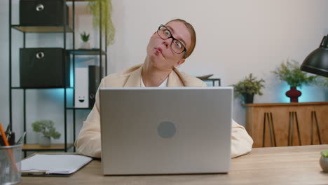 Businesswoman-hiding-behind-laptop-computer,-making-funny-face-fooling-around-putting-his-tongue-out