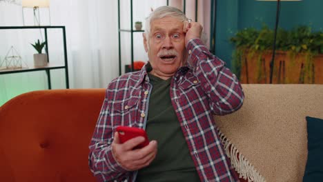 Erstaunt-älterer-Großvater-Nutzt-Mobiles-Smartphone,-Erhält-Gute-Nachrichten-Nachricht-Schockiert-über-Plötzlichen-Sieg