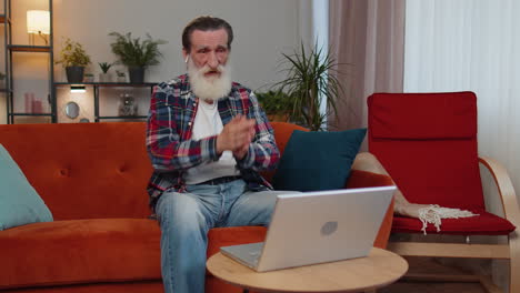 Senior-old-man-looking-at-laptop,-making-video-webcam-conference-call-with-friends-or-family-at-home