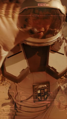 Man-in-spacesuit-turning-on-camera-and-pointing-at-arid-terrain-while-recording-video-message-from-surface-of-Mars.-Vertical-shot