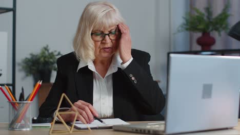 Müde-ältere-Geschäftsfrau-Im-Büro,-Freiberufliche-Lehrerin,-Die-Einen-Laptop-Benutzt-Und-Unter-Migränekopfschmerzen-Leidet