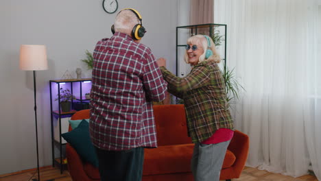 Happy-senior-grandparents-man-woman-listening-music-dancing-disco-fooling-around-having-fun-at-home