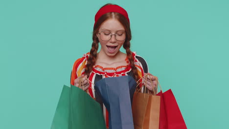 Redhead-girl-showing-shopping-bags,-advertising-discounts,-smiling-looking-amazed-with-low-prices