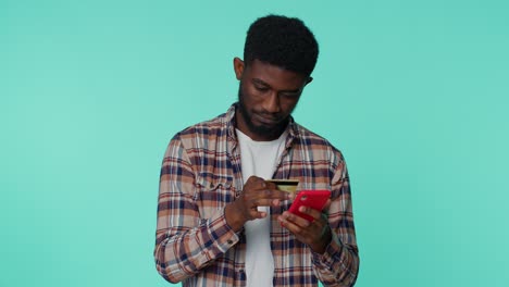 Junger-Mann-Benutzt-Kreditkarte-Und-Smartphone,-Während-Er-Geld-überweist,-Kauft-Online-Ein