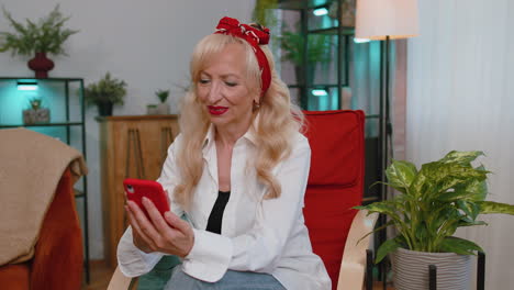 Senior-old-grandmother-sitting-on-chair,-using-smartphone-share-messages-on-social-media-application